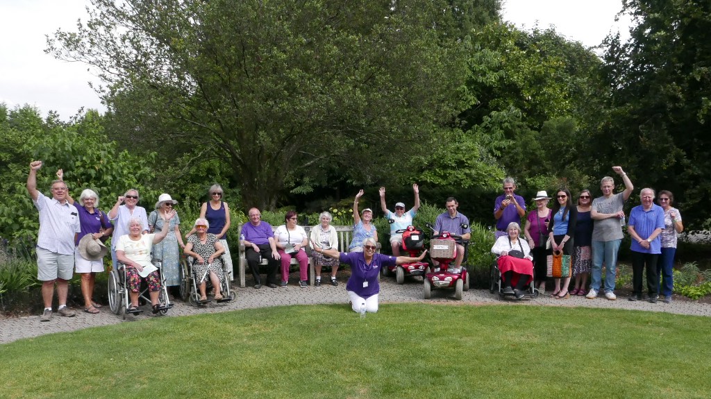 Several people standing and sitting outside in a park.