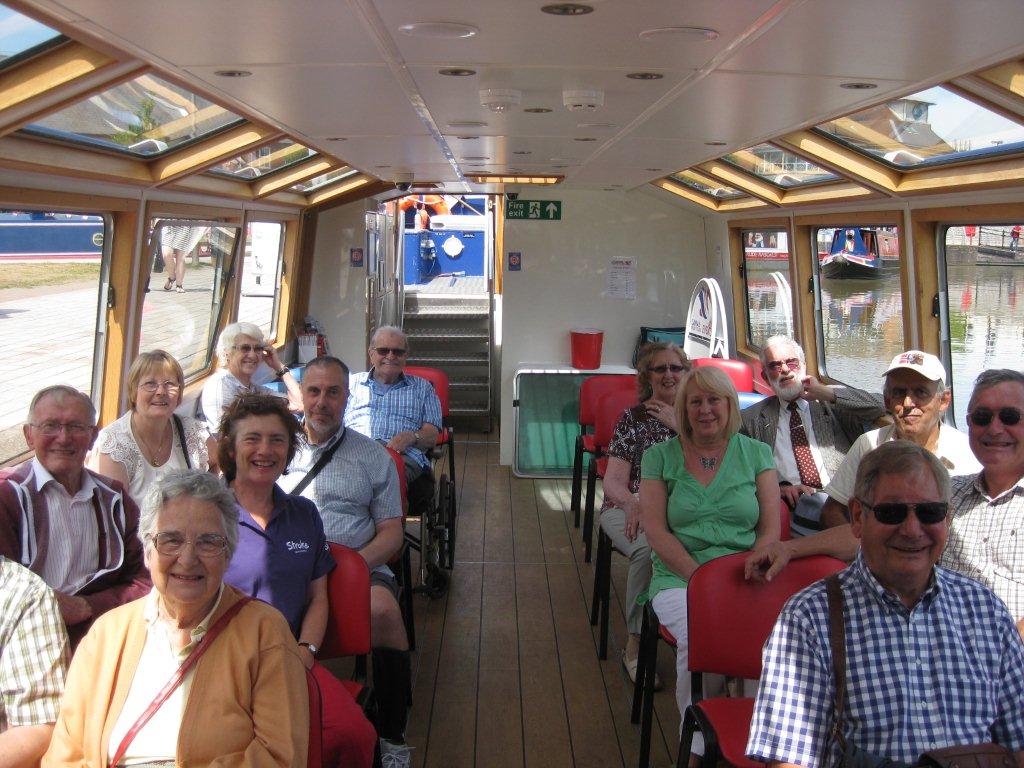 Large group of people sitting on seats inside a boat