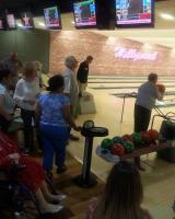 Several people at a bowling alley, some of them watching a man about to bowl.
