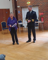 Myra Mitchell standing next to the Executive Officer from HMS Sultan, in the middle of a large room