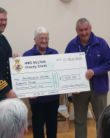 HMS Sultan Charity Chest cheque being held by three men