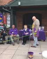 A group of people outside standing and sitting near Stroke Association themed posters and banners.