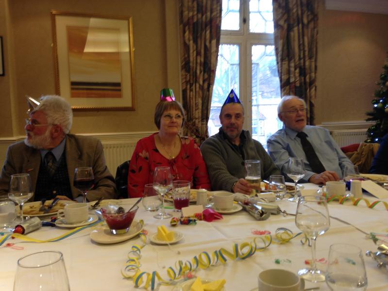 Four people wearing party hats and sitting at a table with decorations on it